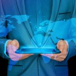 digital transformation mistakes - man holding a tablet with world map on blue background